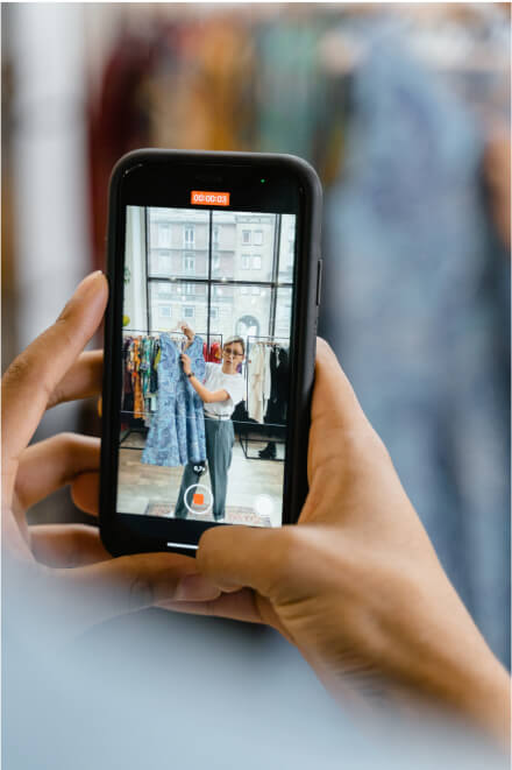 Customer using a mobile phone to photograph clothing in a retail environment